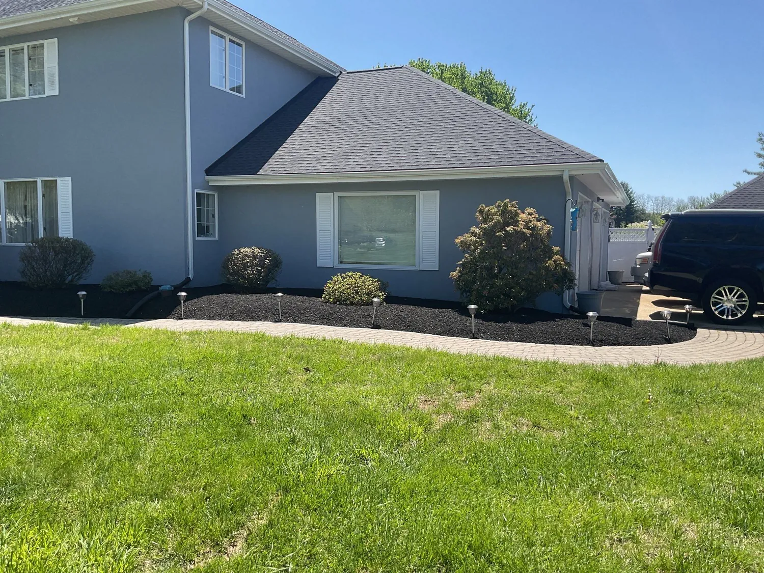 Curved fresh mulch beds framing the front of a two-story home with a manicured green lawn